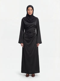 Schwarzes Mira Kleid aus glänzendem Stoff mit Taillenraffung und langen Ärmeln, Frontalansicht.