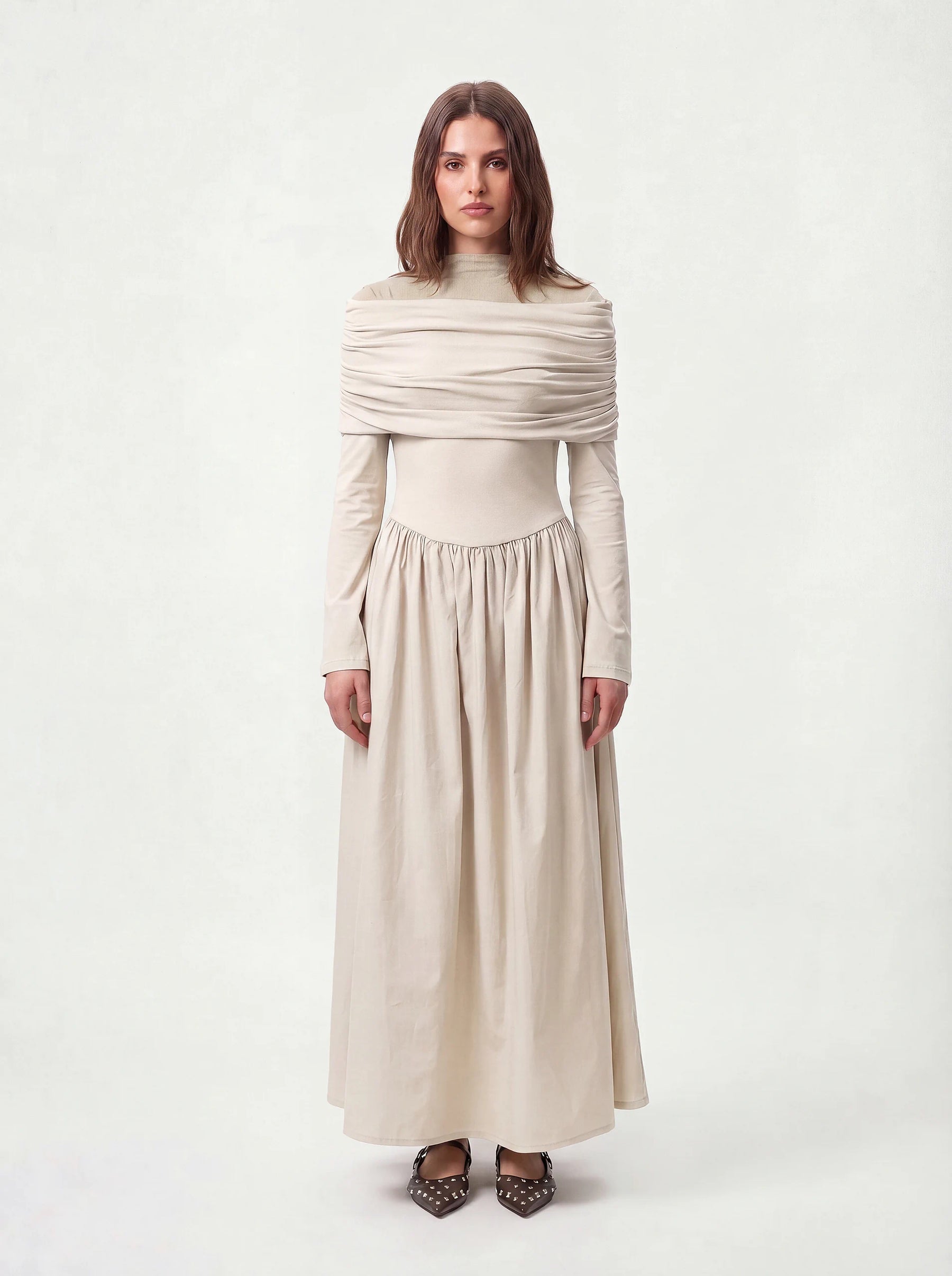 Hellbeige Maxikleid mit Stehkragen, horizontaler Raffung im Schulterbereich und weitem Rockteil, Frontalansicht.