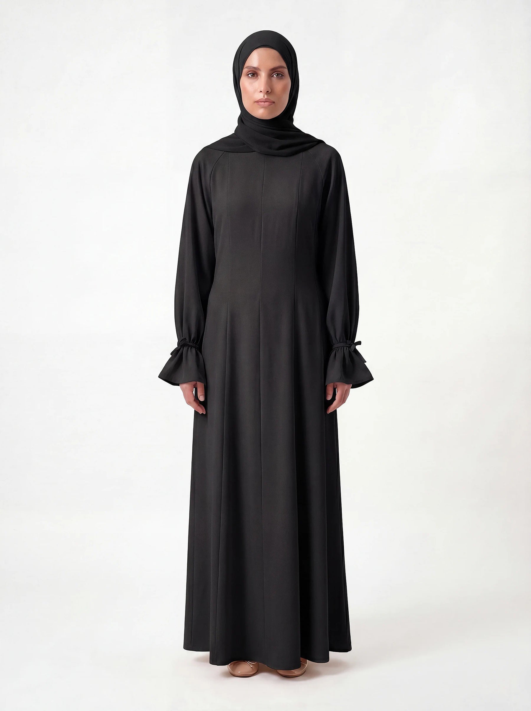 Schwarzes bodenlanges Kleid mit Teilungsnähten und gerafften Ärmelabschlüssen, Frontalansicht.