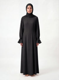 Schwarzes bodenlanges Kleid mit Teilungsnähten und gerafften Ärmelabschlüssen, Frontalansicht.