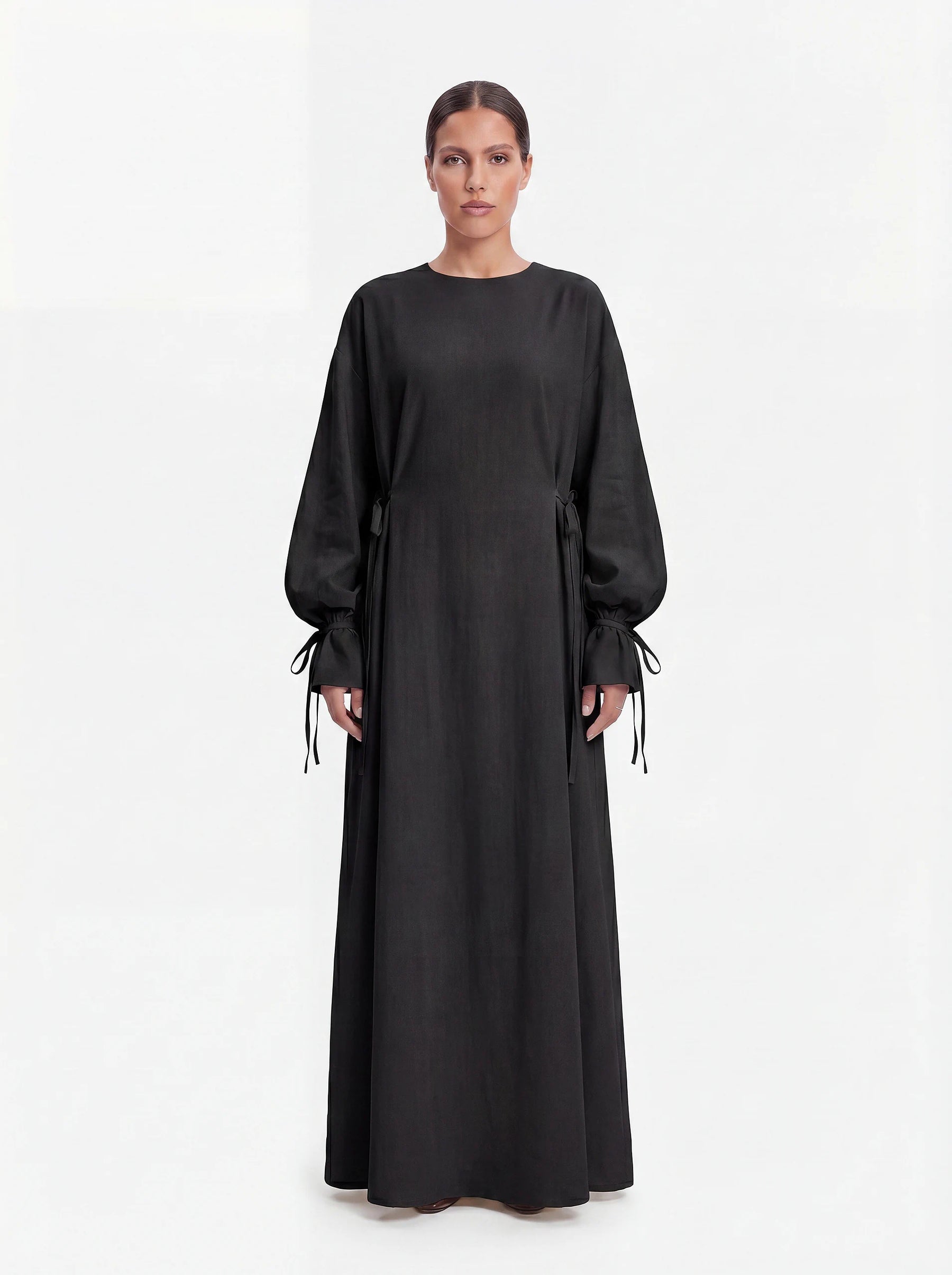 Schwarze Abaya mit Schleifendetails an den Ärmelabschlüssen und der Taille, Frontalansicht.