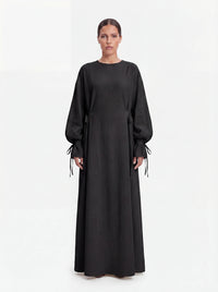 Schwarze Abaya mit Schleifendetails an den Ärmelabschlüssen und der Taille, Frontalansicht.