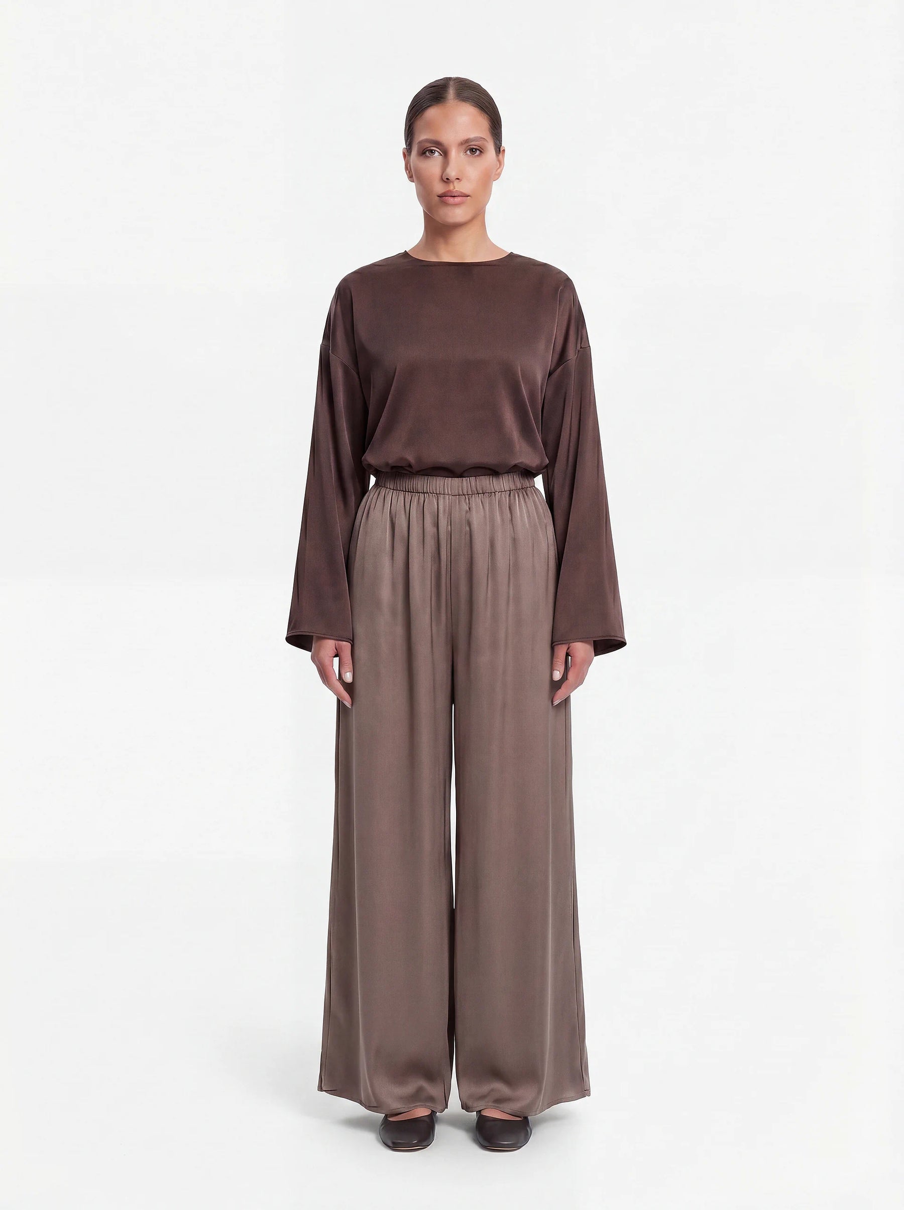 Weit geschnittene Hose in schimmerndem Taupe mit gerafftem Elastikbund und weitem Bein, Frontalansicht.