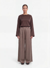 Weit geschnittene Hose in schimmerndem Taupe mit gerafftem Elastikbund und weitem Bein, Frontalansicht.