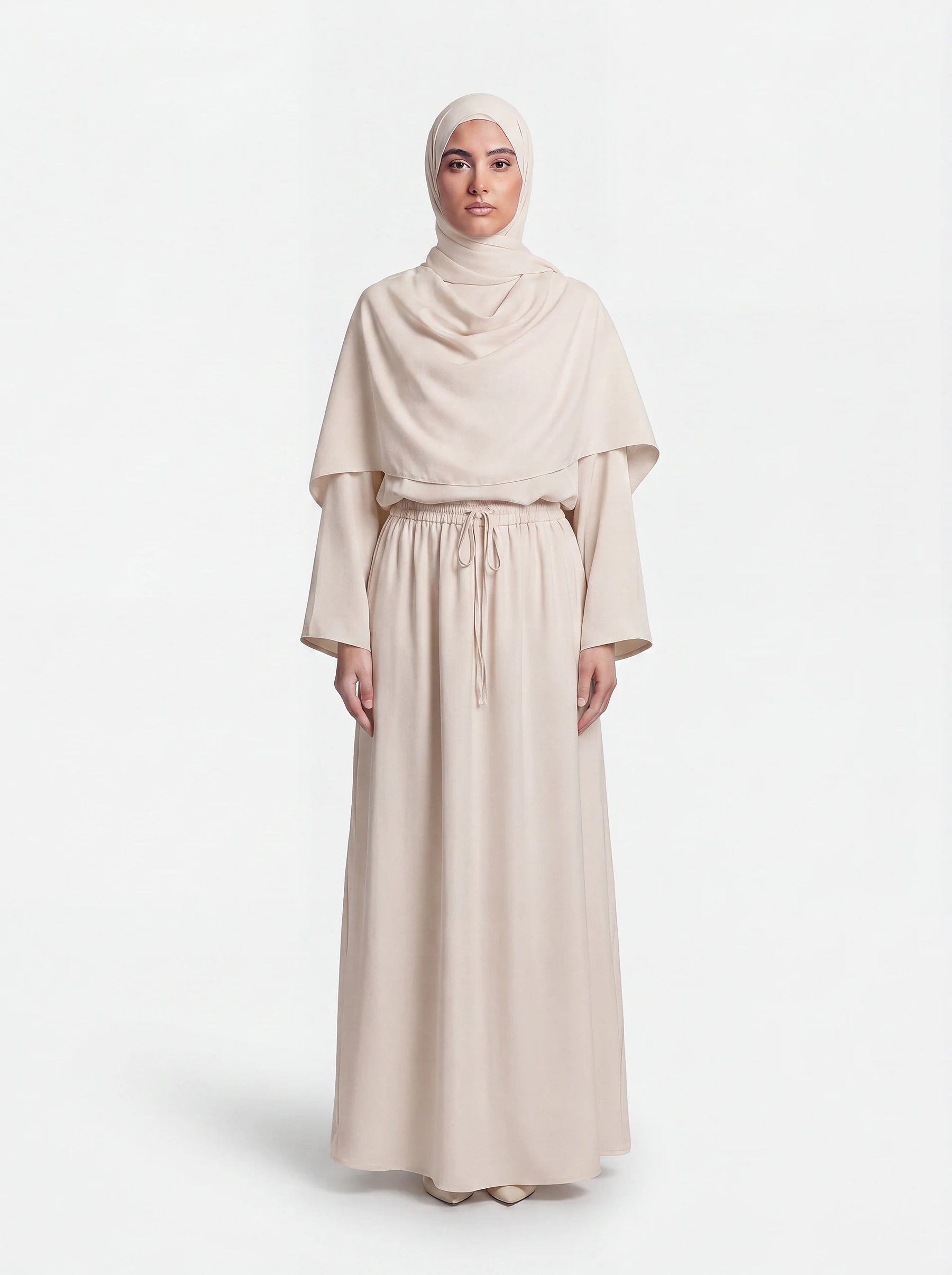Cremebeiger Cape-Zweiteiler mit passendem Hijab und langem Rock mit Tunnelzug, Frontalansicht.