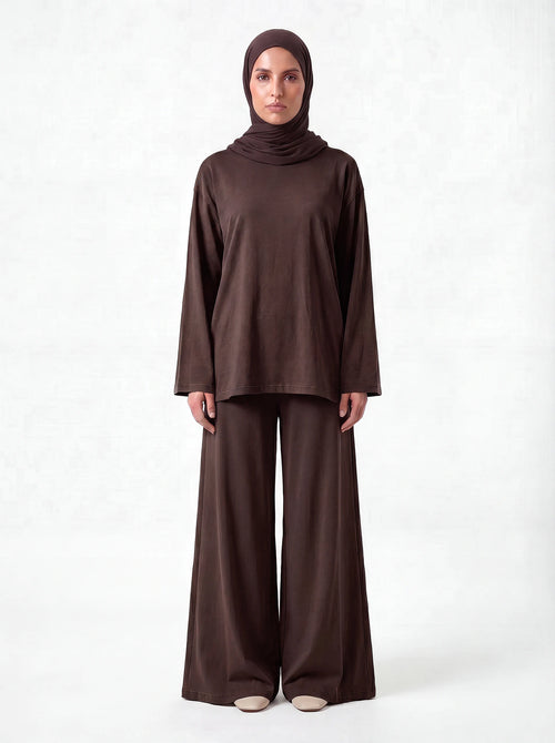 Dunkelbrauner Pullover mit weiten Ärmeln, kombiniert mit weiter Stoffhose, Frontalansicht